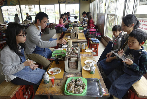 In this Sunday, April 10, 2016 photo, Koji Takemoto, 38, his wife Yuko and three children enjoy baked oysters for lunch despite traffic restrictions and police inspection in a section of Hiroshima City, western Japan, where this year’s Group of Seven foreign ministers’ meeting is being held. Hiroshima is known as Japan’s biggest, and reputedly the best, oyster producer. (AP Photo/Mari Yamaguchi)