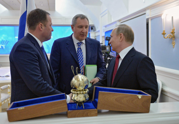 Russian President Vladimir Putin, right, listens to an explanation of Roskosmos CEO Igor Komarov, and deputy premier Dmitry Rogozin, center, during a visit to Roskosmos in Moscow on Tuesday, April 12, 2016. Putin has highlighted Russia's cooperation with the United States in space, despite all of the difficulties the two countries face on Earth. Putin spoke by video link with astronauts from both countries aboard the International Space Station on Tuesday, the day Russia celebrates Cosmonauts Day. It was on April 12, 1961, that Yuri Gagarin orbited the Earth to become the first man in space. (Alexei Druzhinin/Sputnik, Kremlin Pool Photo via AP)