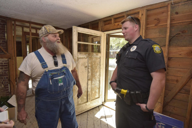 In this Tuesday, March 29, 2016 photo, Columbia Patrolman Michael Thompson speaks with a local contractor working to lift and repair homes near Gills Creek in Columbia, SC., that were heavily damaged in last October's floods. (AP Photo/Richard Shiro)