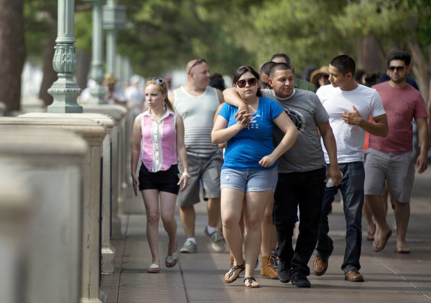 FILE - This June 29, 2013 file photo shows tourists walking along The Strip in Las Vegas. A new report by the Las Vegas tourism board shows visitors are spending more money on their trips to Sin City. The latest statistics come from the Las Vegas Convention and Visitors Authority, which issued its visitor profile study results this month. (AP Photo/Julie Jacobson, File)