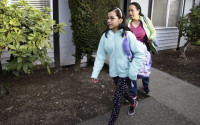 In this photo taken March 31, 2016, Teresa Garcia, right, walks with her daughter, Alondra Miranda, 11, as they leave their apartment for school in Federal Way, Wash., south of Seattle. Garcia, who has spent 14 years in the United States illegally after staying beyond the expiration of her tourist visa in 2002, is one of millions who could be affected when the political fight over immigration comes to the U.S. Supreme Court on Monday, April 18, 2016 as the court weighs the fate of Obama administration programs that could shield roughly 4 million people from deportation and grant them the legal right to hold a job. (AP Photo/Ted S. Warren)