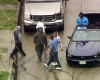 In this image made from a video provided by KABC-TV, two burglary suspects in blue shirts - one standing in the car and one at center left - greet onlookers when they ended the pursuit in a convertible Mustang in South Los Angeles, Thursday, April 7, 2016. The bizarre chase on rainy Southern California streets and highways ended when the pair stopped the car in a South Los Angeles neighborhood, exchanged high-fives with onlookers and took selfies before officers arrived several minutes later and handcuffed them. (KABC-TV via AP) MANDATORY CREDIT TV OUT