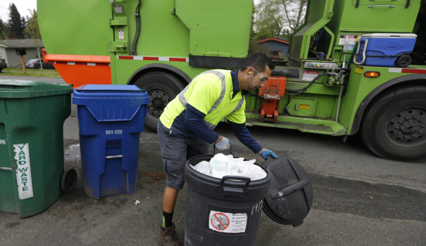 David Morales, a garbage driver with Recology, picks up a garbage container for Seattle Public Utilities, Friday, April 15, 2016, in Seattle.  A judge is scheduled to hear a challenge Friday, April 16, 2016, to a new Seattle law allowing garbage collectors to check people's trash to see whether they are disposing of recycling items and food waste incorrectly.  (AP Photo/Ted S. Warren)