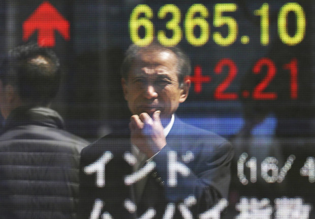 A man is reflected on an electronic board of a securities firm in Tokyo, Friday, April 15 2016. Asian stocks mostly edged lower on Friday as investors assessed a report on Chinese quarterly economic growth while Japanese shares dropped after an earthquake. (AP Photo/Koji Sasahara)