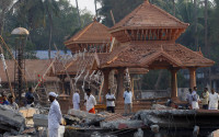 People check out the damaged structures after a massive fire broke out Sunday during a fireworks display at the Puttingal temple complex in Paravoor village, Kollam district, southern Kerala state, India, Monday, April 11, 2016. Medical teams on Monday tended to hundreds of people injured in a massive fire that killed more than a hundred, while authorities searched for those responsible for illegally putting on the fireworks display that caused the weekend blaze. (AP Photo/Aijaz Rahi)