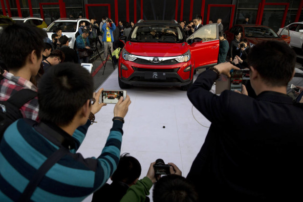 In this photo taken Monday, April 11, 2016, visitors examine the Yuan, BYD's latest Plug-in Hybrid mini SUV introduced at the BYD Dreams Conference in Beijing, China. Industry data released Tuesday, April 12, 2016 show that Chinese auto sales rose by nearly 10 percent last month, led by strong demand for SUVs that more than offset slipping passenger car sales. (AP Photo/Ng Han Guan)