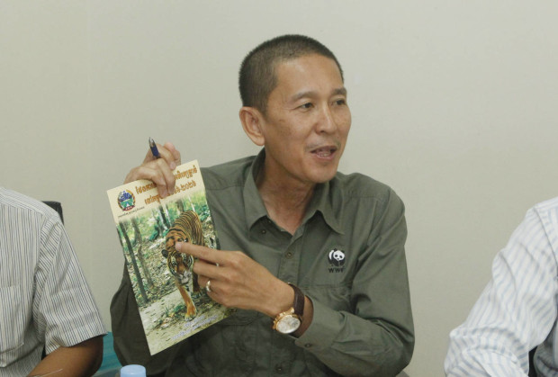 Chhith Sam Ath, Cambodia Director of  World Wildlife Fund, WWF, shows a booklet  during a press conference, in Phnom Penh, Cambodia, Wednesday, April 6, 2016.  Cambodia has unveiled a plan to reintroduce tigers from abroad into the dry forests of the country, where they have become virtually extinct due to poaching. (AP Photo/Heng Sinith)