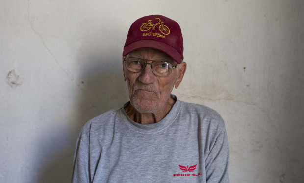 In this April 5, 2016 photo, Pedro Alejandro Lopez, 83, poses for a portrait inside his home on Calle Habana in Old Havana, Cuba. Lopez and his wife moved in their 1918 four-bedroom colonial home on Calle Habana forty years ago. A truck driver from the national electric company, the state let him purchase the home in exchange for monthly payments of 50 pesos over the course of 20 years, the equivalent of about $2 a month, not adjusted for inflation. (AP Photo/Desmond Boylan)