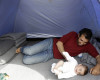 A migrant plays with his baby inside tent at the northern Greek border point of Idomeni, Greece, Thursday, April 14, 2016. More than 12,000 people have been stuck her for more than a month amid hopes that the border would reopen.(AP Photo/Amel Emric)