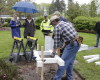 Members of the Olympia Beekeepers Association install a base for bee hive boxes on the front lawn of the governor's mansion as first lady Trudi Inslee, holding umbrella, looks on, in Olympia, Wash., Thursday, April 14, 2016. About 30,000 European honeybees will be placed in the hives next week as part of an effort to raise awareness about the decline of bee populations, as well as to boost pollination of plants on the Capitol campus. (AP Photo/Rachel La Corte)