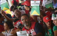 Supporters shout slogans while holding images of the Brazilian Constitution, during a rally of Social Movements for Democracy, in a camp set up by supporters of President Dilma Rousseff in Brasilia, Brazil, Saturday, April 16, 2016. The lower chamber of Brazil's Congress on Friday began a debate on whether to impeach Rousseff, a question that underscores deep polarization in Latin America's largest country and most powerful economy. The crucial vote is slated for Sunday. (AP Photo/Eraldo Peres)