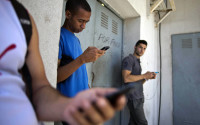 FILE - In this April 1, 2014, file photo, students gather behind a business looking for a Internet signal for their smart phones in Havana, Cuba. As U.S. officials dealt with the fallout of a once-secret "Cuban Twitter" program, they had one thing on their side: notorious delays in the federal Freedom of Information Act. (AP Photo/Ramon Espinosa, File)