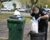 Seattle Police officer Aaron Stoltz searches garbage and recycling bins, Friday, April 15, 2016, after human remains were found in a nearby container in Seattle. Seattle Assistant Police Chief Robert Merner said authorities were investigating the probable connection between the remains found Friday and the recent murder of Ingrid Lyne, whose partial remains were found in a recycling bin earlier in the week. (AP Photo/Ted S. Warren)