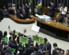 Brazil's Attorney General Jose Eduardo Cardozo, top left, presents the defense of Brazil's President Dilma Rousseff in the Chamber of Deputies, as opposition lawmakers hold signs that read in Portuguese "Goodbye dear" and "Impeachment now" in Brasilia, Brazil, Friday, April 15, 2016.  The lower chamber of Brazil's Congress began the debate on whether to impeach Rousseff, a question that underscores deep polarization in Latin America's largest country and most powerful economy. The crucial vote is slated for Sunday. (AP Photo/Eraldo Peres)