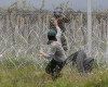 A migrant man trying to remove barbed wire along the fence clashes with Macedonian police at the northern Greek border point of Idomeni, Greece, Wednesday, April 13, 2016. New clashes have broken out between Macedonian police and stranded refugees and other migrants trying to scale a fence on Greece's border with the country. (AP Photo/Amel Emric)