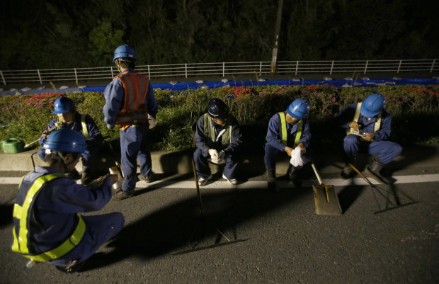 Workers take a break as they repair the damaged road in Kumamoto, southern Japan, Saturday, April 16, 2016.  After two nights of earthquakes flattened houses and triggered major landslides in southern Japan, dozens of residents of the town of Ozu have slept in their cars at a public park.(AP Photo/Shizuo Kambayashi)