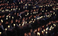 High school students hold candles to pay their respects to the victims of the sunken ferry Sewol during a ceremony on the eve of the second anniversary of the ferry sinking in Ansan, South Korea, Friday, April 15, 2016. Two year ago, as South Korea writhed in grief and fury after more than 300 people, most of them school kids, drowned in a ferry sinking, it seemed things would never be the same.(AP Photo/Ahn Young-joon)