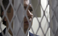 FILE - In this July 9, 2015, Gustavo Martinez, son-in-law of Guatemala's President Otto Perez Molina, stands inside a court holding cell in Guatemala City. Martinez, who had served until April 2015, as the president's private secretary, was arrested based on investigations by the federal prosecutors' office and the U.N. International Commission Against Impunity in Guatemala for alleged influence trafficking. Martinez was eventually freed, but then arrested again on April 15, 2016, for alleged involvement in irregularities also involving his father-in-law. (AP Photo/Luis Soto, File)