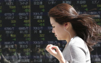 A woman walks by an electronic stock board of a securities firm in Tokyo, Friday, April 15, 2016. Asian stocks mostly edged lower on Friday as investors assessed a report on Chinese quarterly economic growth while Japanese shares dropped after an earthquake. Market players were also watching for cues on currencies and other policies from a meeting in Washington, D.C., of financial ministers and central bank governors of the Group of 20 leading industrial nations. (AP Photo/Koji Sasahara)