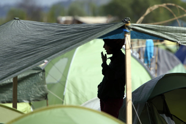 A migrant stands inside a tent at the northern Greek border point of Idomeni, Greece, Thursday, April 14, 2016. More than 12,000 people have been stuck her for more than a month amid hopes that the border would reopen.(AP Photo/Amel Emric)