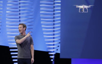 Facebook CEO Mark Zuckerberg points to a drone flying behind him during his keynote address at the F8 Facebook Developer Conference Tuesday, April 12, 2016, in San Francisco.  Zuckerberg said Facebook is releasing new tools that businesses can use to build "chatbots," or programs that can talk to customers in conversational language.  (AP Photo/Eric Risberg)