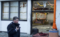 A police officers stand passes by a Sikh temple after three people have been injured in an apparently deliberate explosion Saturday evening, April 16, 2016 in the western German city of Essen.  A spokesman for Essen police told The Associated Press that a masked person is reported to have fled the scene shortly after the blast. (Marcel Kusch/dpa via AP)