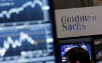 FILE - In this Oct. 16, 2014, file photo, a screen at a trading post on the floor of the New York Stock Exchange is juxtaposed with the Goldman Sachs booth. The Justice Department announced a $5 billion settlement with Goldman Sachs over the sale of mortgage-backed securities leading up to the 2008 financial crisis. The deal announced Monday, April 11, 2016, resolves state and federal probes into the sale of shoddy mortgages before the housing bubble and economic meltdown.  (AP Photo/Richard Drew, File)