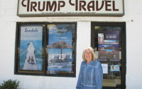 In this April 6, 2015 photo, Claudia Rabin-Manning stands outside her Baldwin, N.Y. business, Trump Travel. Rabin-Manning says she has been the target of legal action from Republican presidential candidate Donald Trump over the use of the name Trump Travel. She explains the business name has nothing to do with the businessman, and instead was named by a previous owner of the travel agency who played canasta, where the "trump card" is used in the game. (AP Photo/Frank Eltman)