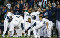 Seattle Mariners' Dae-Ho Lee (10) is greeted at the plate by teammates after he hit a walk-off two-run home run in the tenth inning of a baseball game against the Texas Rangers, Wednesday, April 13, 2016, in Seattle. The Mariners beat the Rangers 4-2 in ten innings. (AP Photo/Ted S. Warren)