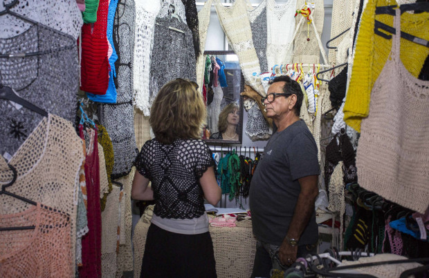 In this April 4, 2016 photo, salesman Victor Rodriguez helps a customer at his stall in the Almacenes San Jose in Havana, Cuba. Rodriguez imagines a future Cuban economy where he can import large quantities of thread, export his women’s clothing to other countries and not have to worry about obtuse state regulations governing everything down to where exactly he can place items at his small retail stand. (AP Photo/Desmond Boylan)