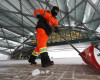 Maintenance man Joseph Dominguez uses a shovel to clear snow between the main terminal of Denver International Airport and the adjoining hotel as a severe spring storm packing high winds and heavy, wet snow sweeps over the intermountain West early Saturday, April 16, 2016, in Denver. A spring snowstorm expected to dump up to several feet of snow along the eastern foothills of Colorado and Wyoming is getting a late start, but the National Weather Service says snow is expected to begin piling up Saturday and Sunday. Airlines at Denver International Airport canceled hundreds of flights Saturday. (AP Photo/David Zalubowski)