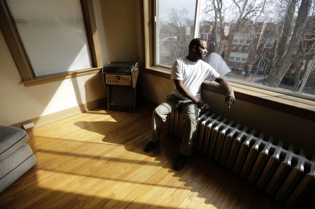 In this March 8, 2016 photo, Darnell Johnson, 50, a resident of a sober home in Chicago, looks out the window of his apartment. Johnson says he was a "weekend social drinker, but it would last all day." Now when he smells alcohol or sees how it affects others, he remembers the bad times. (AP Photo/M. Spencer Green)