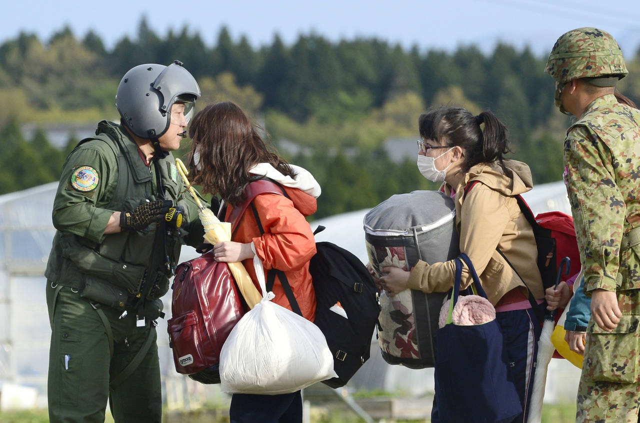College students with their belongings wait for the arrival of a helicopter of the Japan Self-Defense Forces to be transferred to safer place in Minamiaso village, Kumamoto prefecture, Japan, Saturday, April 16, 2016. The powerful earthquake struck southwestern Japan early Saturday, barely 24 hours after a smaller quake hit the same region. (Hiroko Harima/Kyodo News via AP) JAPAN OUT, MANDATORY CREDIT