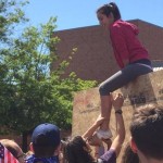 An anti-Trump UW student mocks the Trump supporters' wall by climbing over it. (Brandon Haddix)