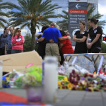 
              Carl Hill, from the Billy Graham Rapid Response Team, prays with a group of women near a memorial for the victims of the Pulse nightclub shooting set up ouside Orlando Health, Thursday, June 16, 2016, in Orlando, Fla. (Jacob Langston/Orlando Sentinel via AP) MAGS OUT; NO SALES; MANDATORY CREDIT
            