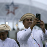 
              Men dressed in traditional Panamanian "pintado" hats and "camisilla" shirts wait as the Neopanamax cargo ship, Cosco Shipping Panama, prepares to cross the new new Agua Clara locks, part of the Panama Canal expansion project, near the port city of Colon, Panama, Sunday, June 26, 2016. The ship carrying more than 9,000 containers entered the newly expanded locks that will double the Panama Canal's capacity in a multibillion-dollar bet on a bright economic future despite tough times for international shipping.  (AP Photo/Moises Castillo)
            