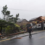 An officer walks past storm debris on Laneda Avenue after a tornado reportedly touched down on Friday, Oct. 14, 2016, in Manzanita, Ore. (Danny Miller/Daily Astorian via AP)