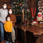 During the first COVID pandemic Christmas of 2020, Arthur & Associates' Santa photos included masks for everyone, and a plexiglass shield between Santa and visitors. (Courtesy Arthur & Associates)