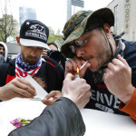 Mark Burrell, right, and a man who said he goes by the name Abundis, left, light marijuana joints Monday, May 1, 2017, during a May Day protest in Seattle. The two men identify with constitutionalist and libertarian ideals and had been arguing with counter protesters when they decided to smoke pot together with their opponents. (AP Photo/Ted S. Warren)