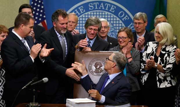 Washington Gov. Jay Inslee, center, shakes hands after he signed a new two-year state operating bud...