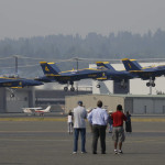 Spectators watch as four members of the U.S. Navy Blue Angels flight team take off, Thursday, Aug. 3, 2017, from Boeing Field in Seattle. The Angels were headed to practice for their weekend performances in the Seafair Air Show. (AP Photo/Ted S. Warren)