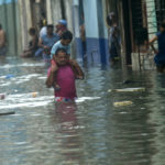 
              A man carries a child on his shoulders as he walks on a flooded street in Havana, after the passing of Hurricane Irma in Cuba, Sunday, Sept. 10, 2017. The powerful storm ripped roofs off houses, collapsed buildings and flooded hundreds of miles of coastline after cutting a trail of destruction across the Caribbean.There were no immediate reports of deaths in Cuba, a country that prides itself on its disaster preparedness, but authorities were trying to restore power and clear roads. (AP Photo/Ramon Espinosa)
            