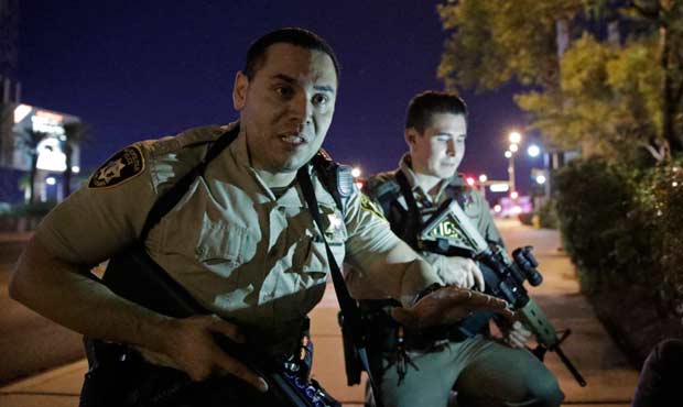 Police officers advise people to take cover near the scene of a shooting near the Mandalay Bay reso...