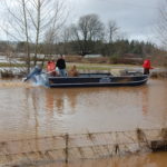 A boat carries supplies up a submerged road in Centralia. (WSDOT)