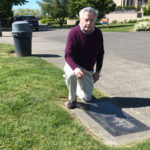James Kemp-Slaughter kneels at the Vancouver monument on Queen Anne Hill that was a signature project of his late brother, McClure Middle School history teacher Michael Kemp-Slaughter. (Feliks Banel)