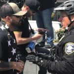 Patriot Prayer's Joey Gibson talks with police as his Conservative demonstration sets up at Westlake Park on May Day 2018. (Hanna Scott, KIRO Radio)