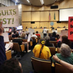 Members of the public look on at a Seattle City Council meeting where the council was expected to vote on a "head tax" Monday, May 14, 2018, in Seattle. The council is to vote on a proposal to tax large businesses such as Amazon and Starbucks to to raise money to fight homelessness. (AP Photo/Elaine Thompson)