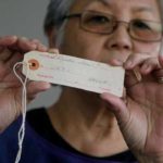 Satsuki Ina holds up an identification tag on Feb. 10, 2017 that wasissued to her mother, Shizuko Ina, at her home in Oakland, Calif. (AP Photo/Jeff Chiu)