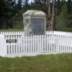 The monument stands along the edge of a road on JBLM, and is surrounded by a white picket fence. (Feliks Banel)