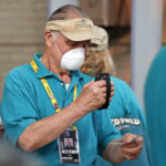 Seattle Mariners ticket taker Franklin Masion wears a mask to help protect against smoky skies as he checks a fan's ticket before a baseball game against the Houston Astros, Monday, Aug. 20, 2018, in Seattle. Smoke from wildfires clogged the sky across the U.S. West, blotting out mountains and city skylines from Oregon to Colorado, delaying flights and forcing authorities to tell even healthy adults in the Seattle area to stay indoors. (AP Photo/Elaine Thompson)